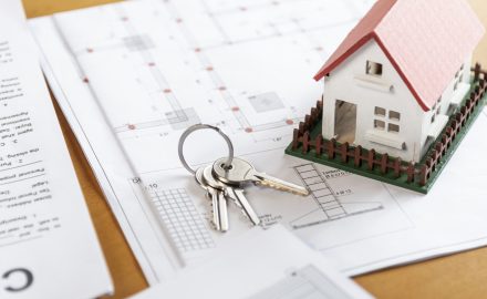chaves e miniatura de casa sobre plantas de imóvel representando segurança ao alugar imóvel com a Razuk
