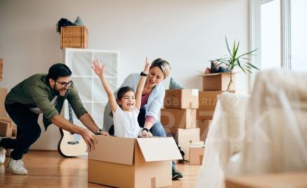 Família feliz se mudando para casa alugada em Campo Grande MS, com caixas de mudança em ambiente residencial